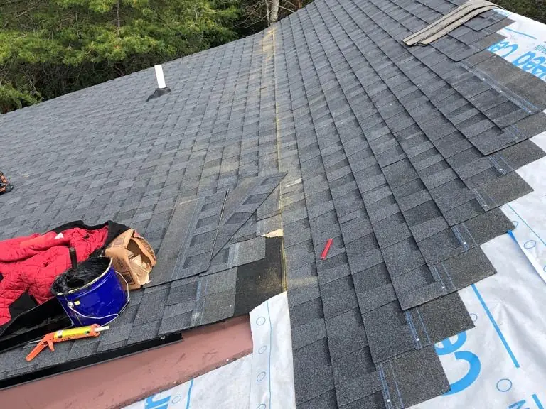 New shingles being installed by hand over underlayment